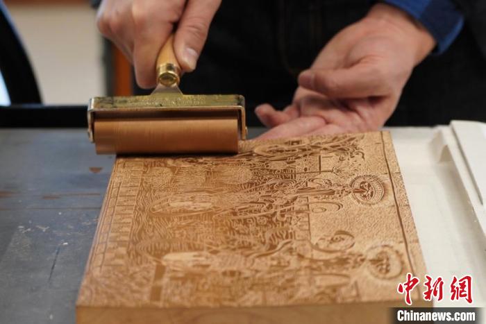 圖為徐晉林工作室工作人員正在給雕好壁畫的版面滾油墨?！【琶赖┰?　攝