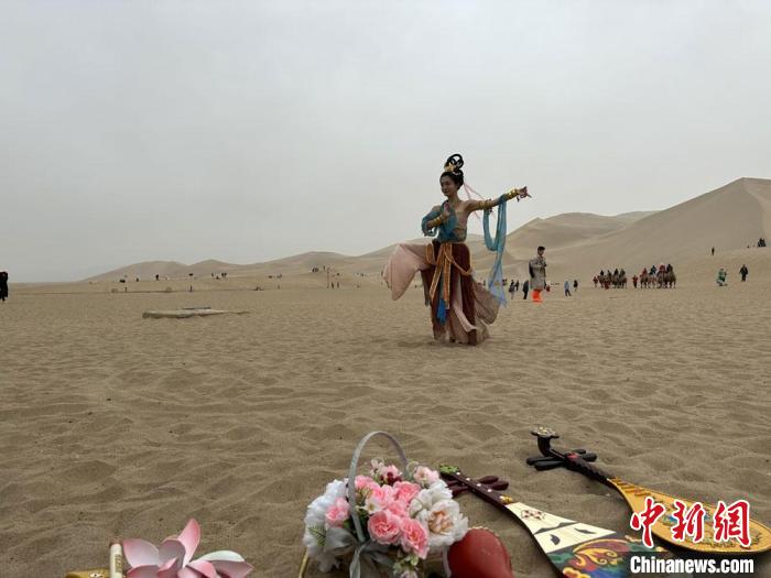 圖為2023年4月底，敦煌大漠“逐舞者”奧楠在鳴沙山月牙泉景區(qū)視頻直播敦煌舞。　馮志軍 攝