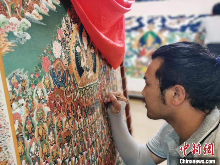 圖為更登才讓的徒弟繪畫唐卡?！?zhí)砀?攝