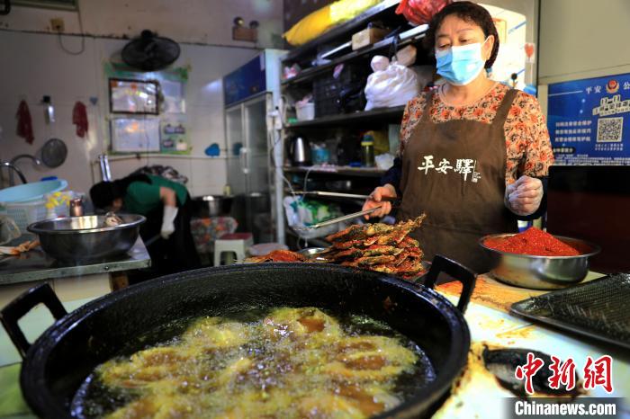 圖為平安驛·河湟民俗文化體驗地內(nèi)的商戶炸干板魚。　薛蒂 攝