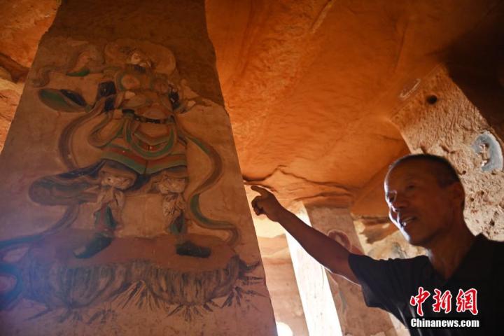 7月15日，甘肅省平?jīng)鍪袥艽h百里石窟長(zhǎng)廊羅漢洞石窟內(nèi)，該窟文保員郭建平介紹窟內(nèi)石刻彩繪壁畫(huà)。郭建平家中三代人曾自發(fā)保護(hù)羅漢洞石窟。羅漢洞石窟遺存40余個(gè)窟龕，以北魏至清代風(fēng)格為主。中新社記者 李亞龍 攝</p>
<p>